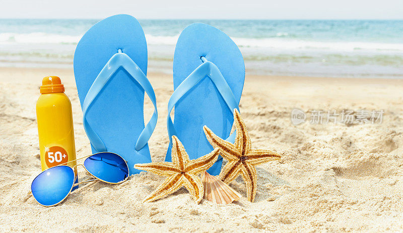 静物由人字拖、太阳镜、防晒乳液和沙滩上的两只海星组成。