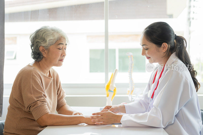 家庭医生在医院用听诊器检查微笑的亚洲老妇人一位老妇人正在向医生咨询整骨病的问题。健康及健康概念