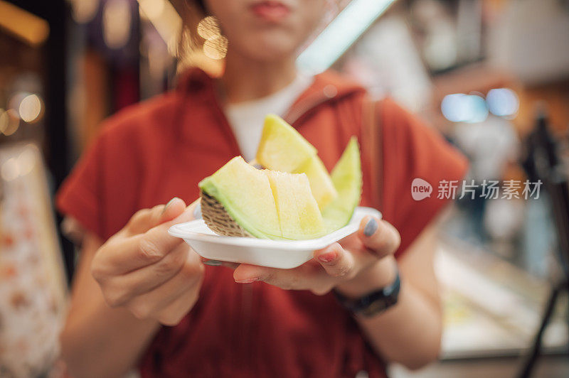 广角观看亚洲人在大阪新关的木串上享用日本水果