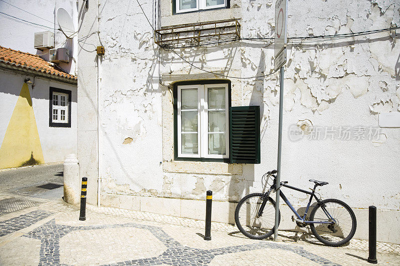 葡萄牙卡斯凯伊斯的城市街道上有白色的房子和一辆停着的自行车。白天的城市景观。
