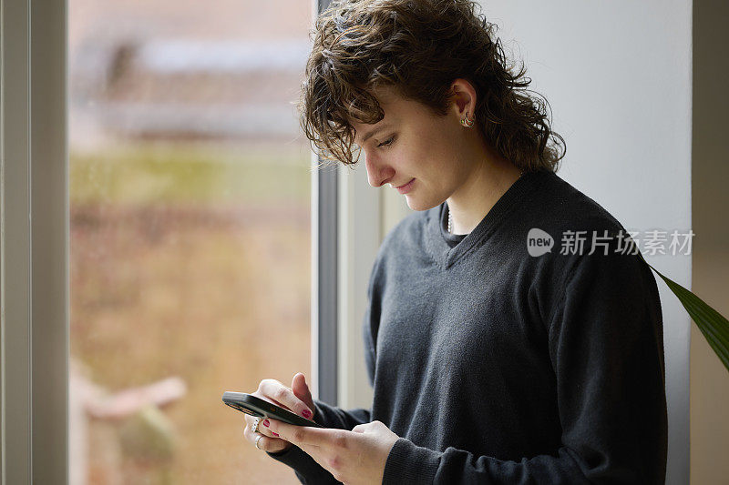 拿着智能手机站在窗口的女人