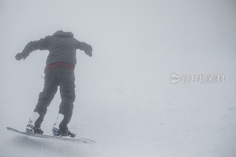 一个男性滑雪板运动员在冬天的一天从山上滑下