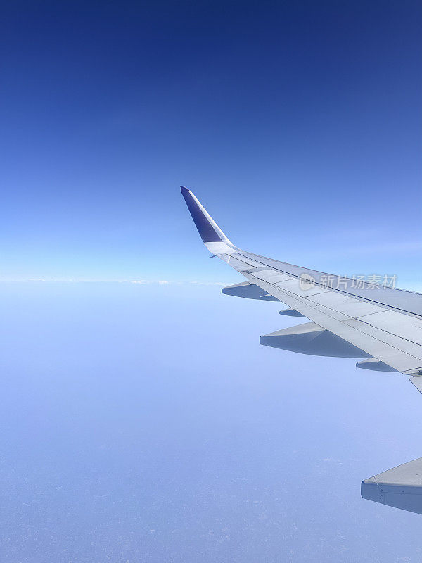 从飞机窗口看到的图像，在云层上看到的飞机机翼，蓬松的白云，小翼和板条，重点是前景