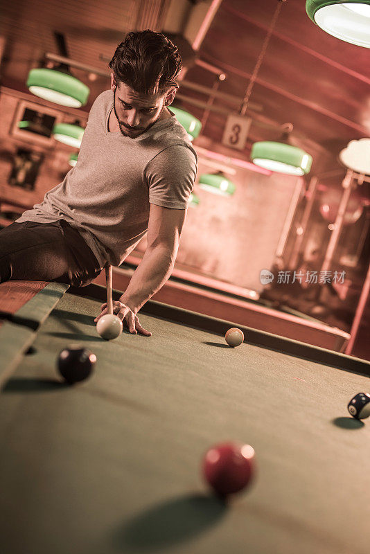 一个熟练的年轻人在酒吧里打台球。