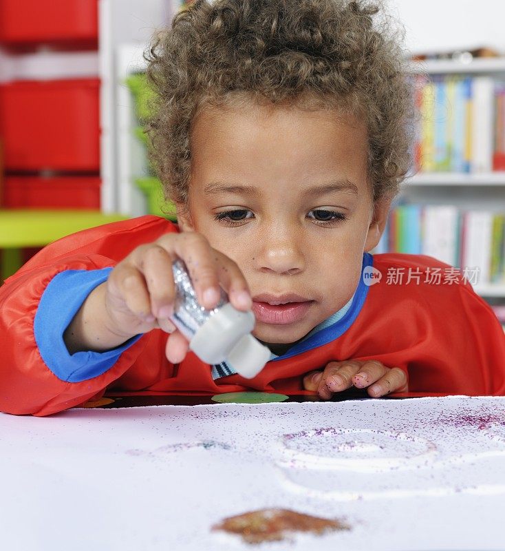 学前儿童使用胶水和亮片创造艺术的特写