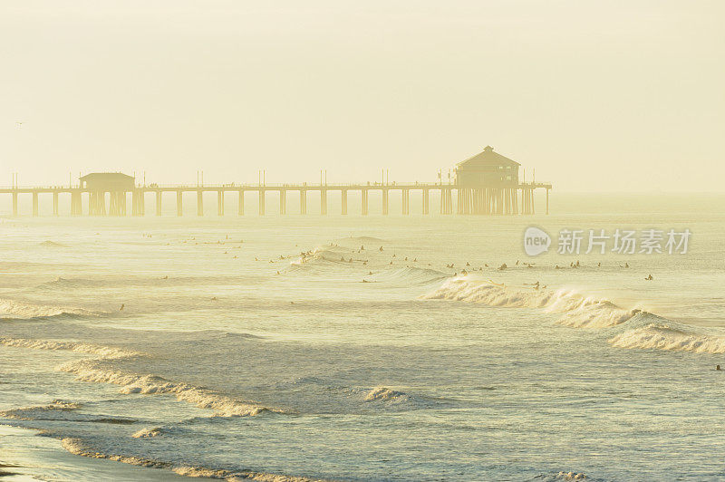 日出时的海滩码头和冲浪者