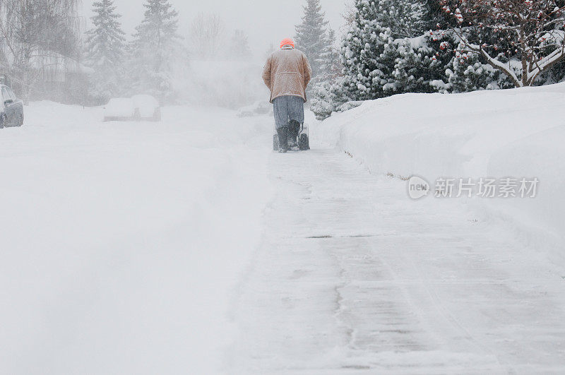 暴风雨中推着吹雪机的人