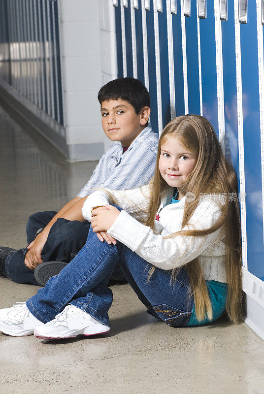 女孩和男孩坐在学校走廊的储物柜旁