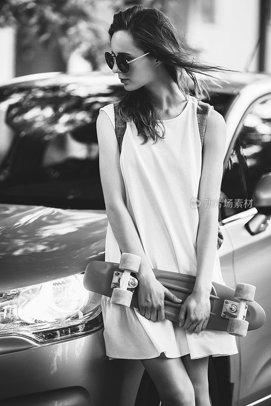 漂亮女孩站在一辆车旁边