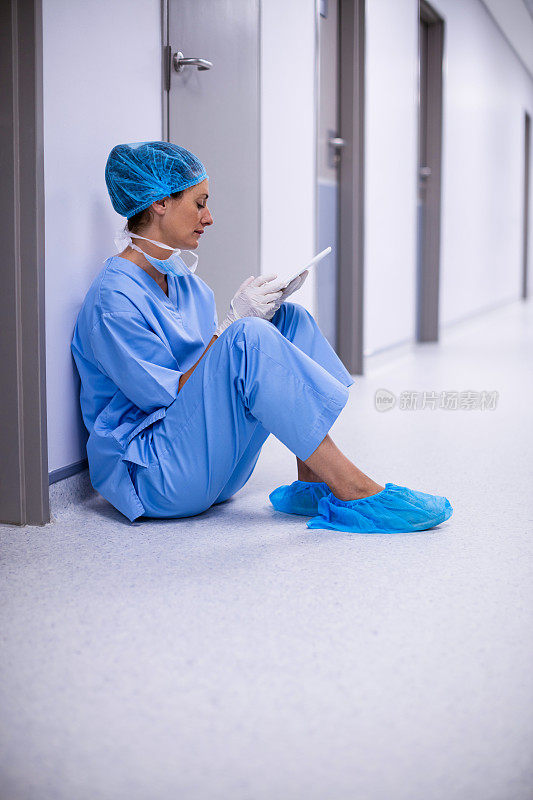 外科医生坐在地板上使用平板电脑