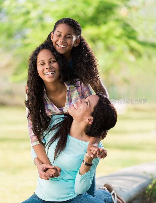 一位拉丁母亲微笑着看着她的女儿们