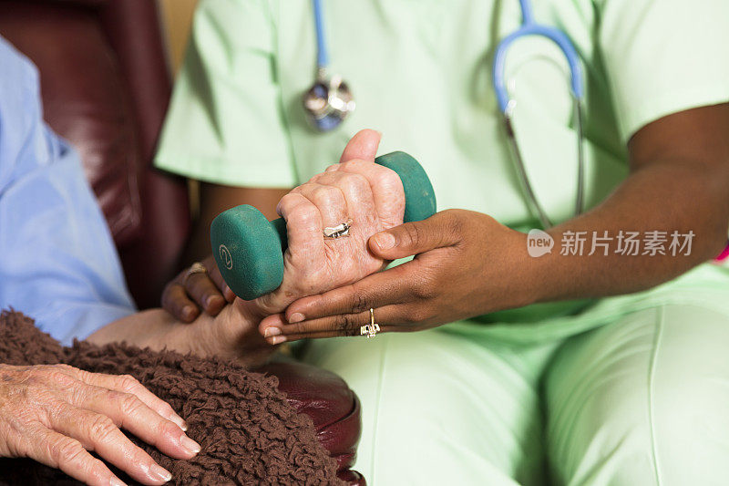 医疗:家庭保健护士帮助妇女在手腕手术后锻炼。