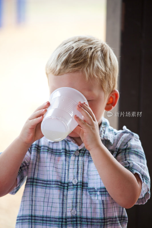 用塑料杯喝水的男孩