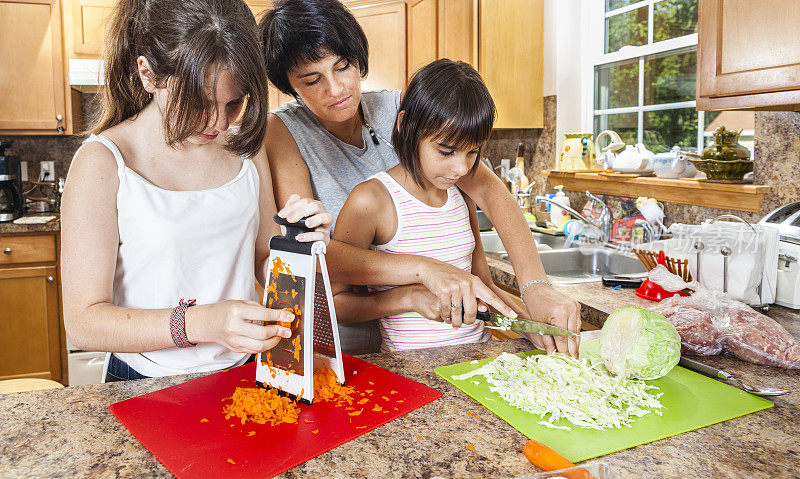 一家人，母亲和两个女儿，切蔬菜做沙拉