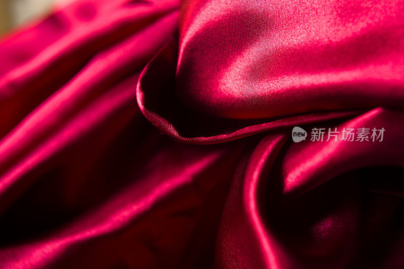 红色缎子或丝绸背景。织物上的波纹。