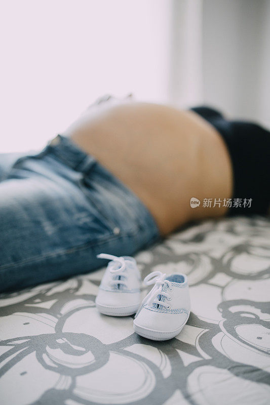 宝宝的鞋子放在怀孕的肚子上