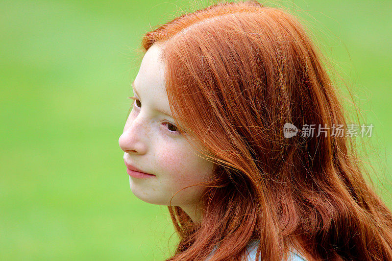 年轻的女孩与长红头发在花园里微笑，白日梦