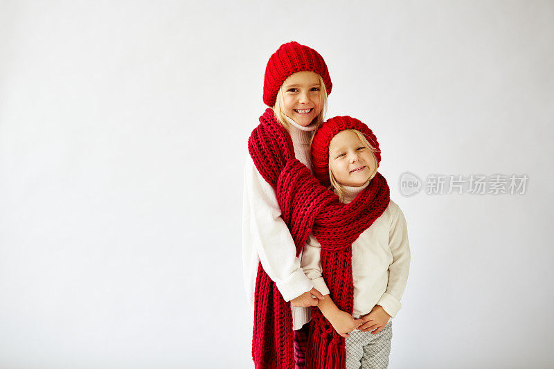 可爱的小妹妹们戴着温暖的针织帽子和围巾