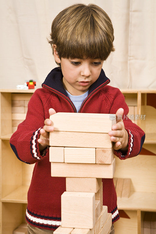 一个小男孩在用积木搭一座塔