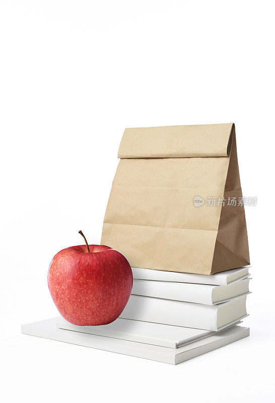 把空白的书和苹果堆在一起，把午餐装在白色的纸上