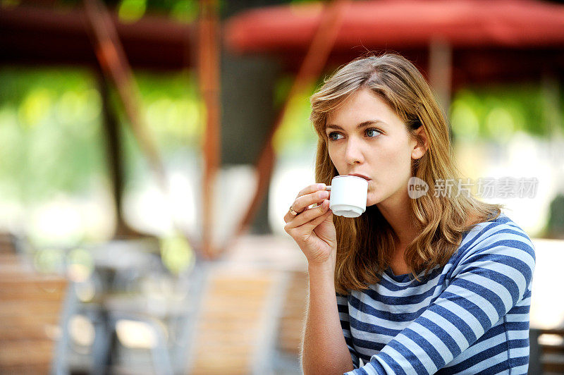 一位年轻女子在巴黎公园咖啡馆里喝着咖啡