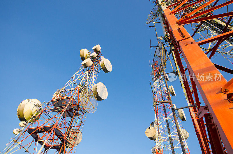 电信塔在蓝天上，一红一白，另一白，天线用于电视、收音机和移动电话。