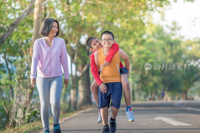 家庭运动快乐活跃的母亲和孩子在户外慢跑，在森林里跑步