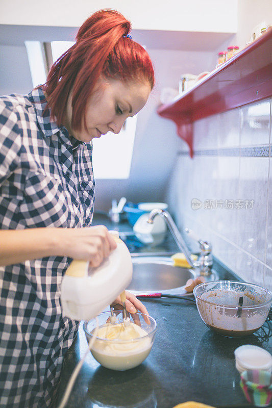 美丽的女人在家里准备饼干和松饼。