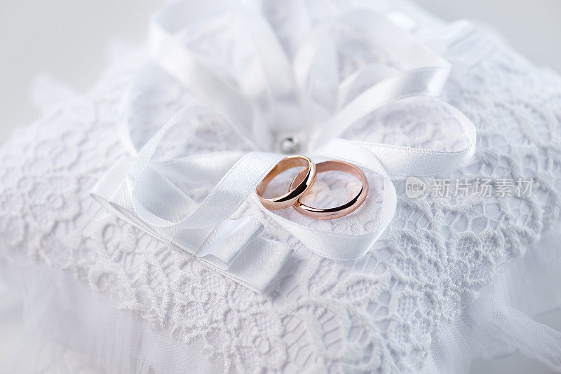 近距离观看金色的结婚戒指上装饰的白色蕾丝枕头