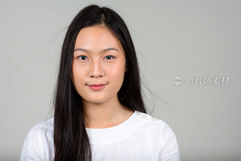 年轻美丽的亚洲妇女与长直发穿着白色衬衫对白色背景