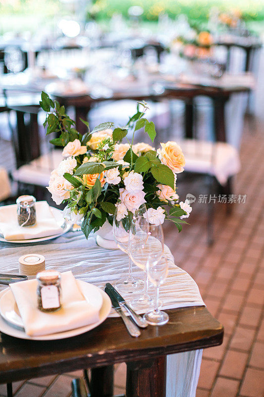 饮食、文化、装饰理念。一束用不同颜色的玫瑰做成的完美的玫瑰放在花园餐厅的桌子上，作为庆祝的盘子和餐具