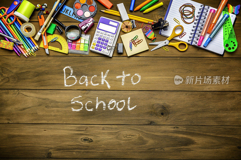 “回到学校”的标志在头顶拍摄的木桌与学校办公用品的框架