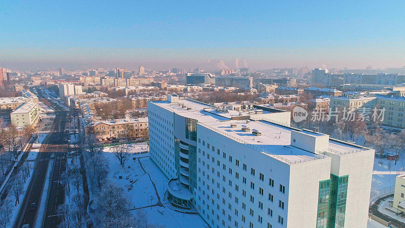 在晴朗寒冷的日子里，鸟瞰被雪覆盖的冬季城市全景。轨道摄影机运动。