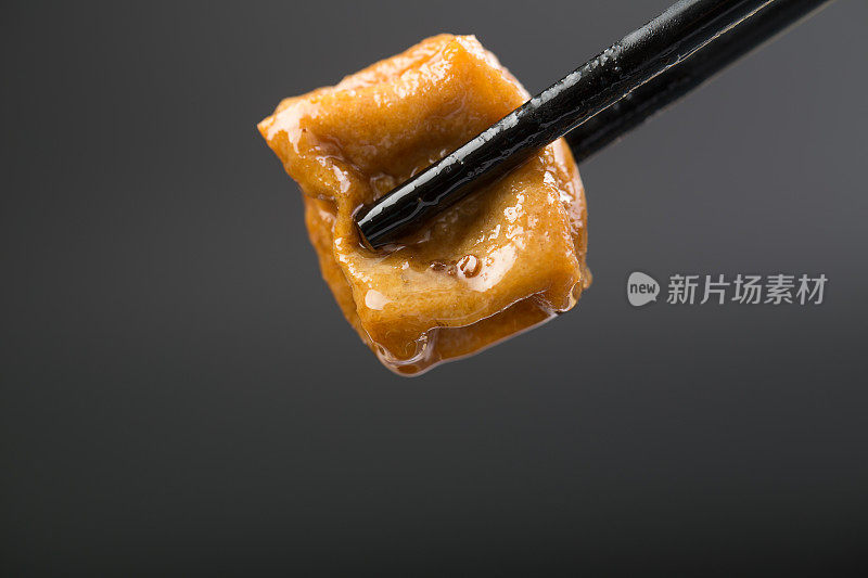 用筷子夹紧的油炸豆腐