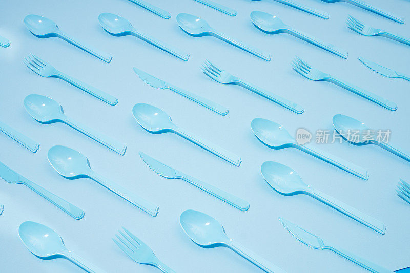 蓝色背景的塑料餐具、汤匙、刀叉