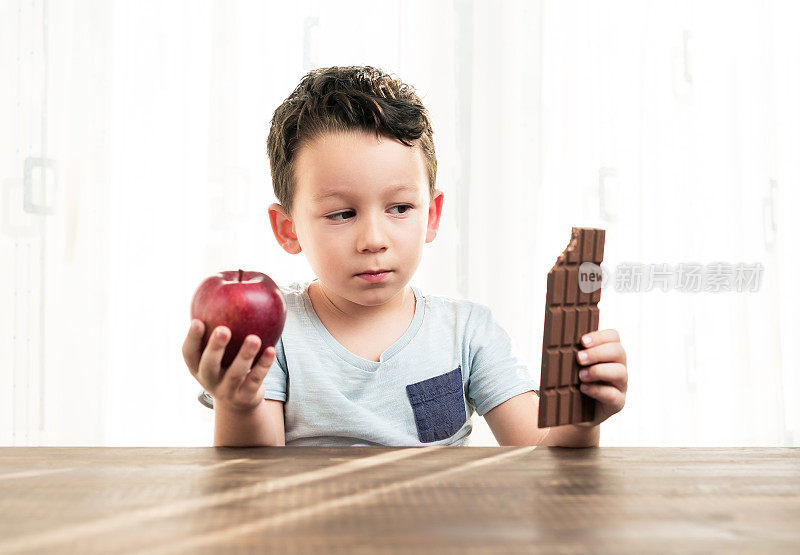 孩子正在巧克力和苹果之间做选择。