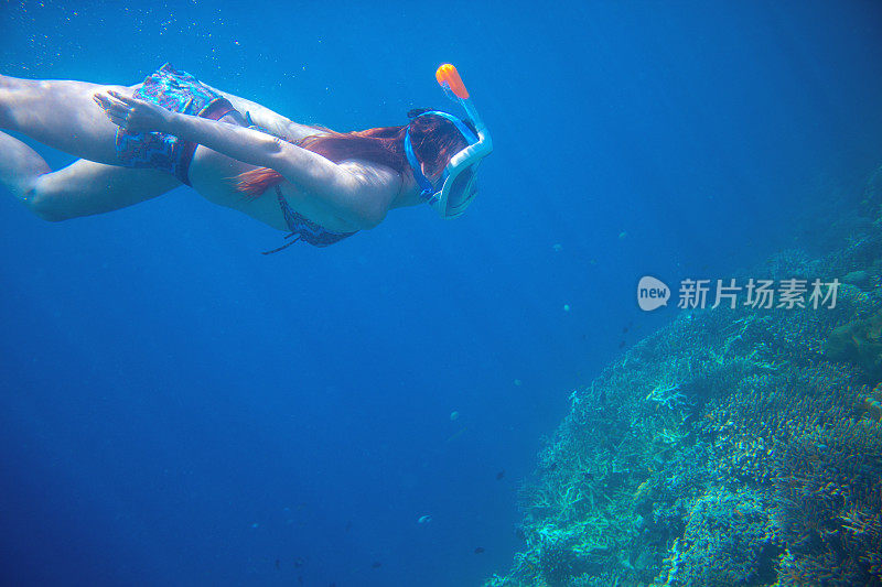潜水女孩与珊瑚礁水下。戴上面罩呼吸。