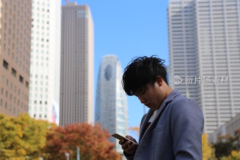 一个年轻人在高楼林立的街道上检查邮件