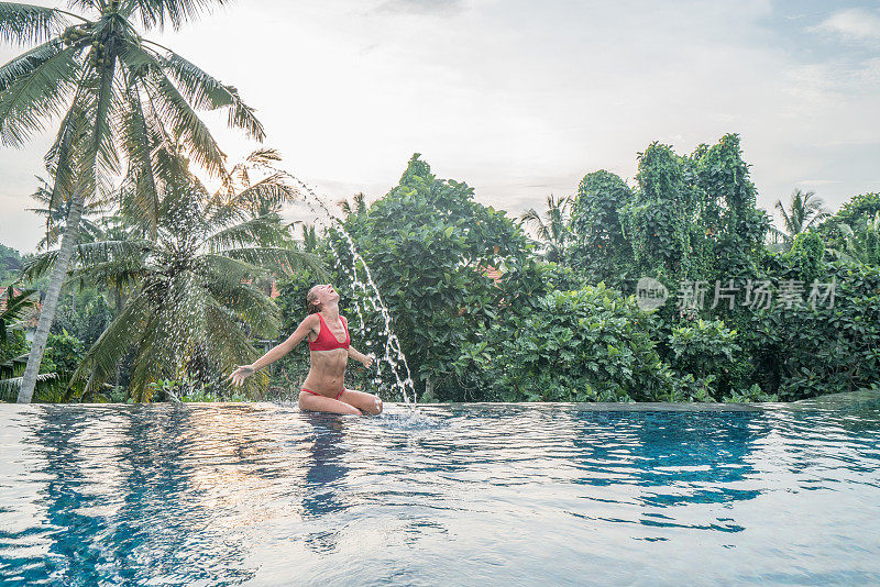 年轻女子在游泳池里扔头发在水里-印度尼西亚巴厘岛-人们ravel有趣的度假胜地概念