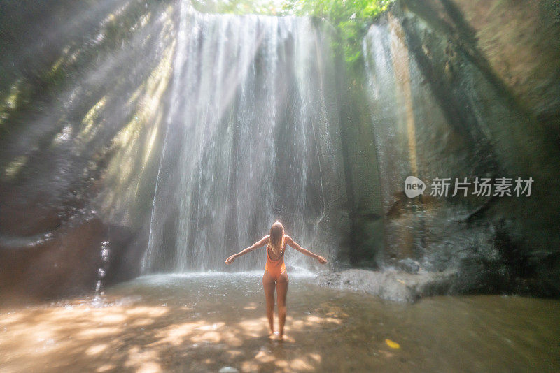 在巴厘岛的热带雨林中，旅行的年轻女子张开双臂拥抱大自然的美丽。人们以自然为旅游理念。