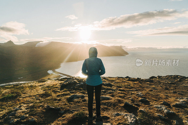 穿着蓝色雨衣的女人看着峡湾的风景