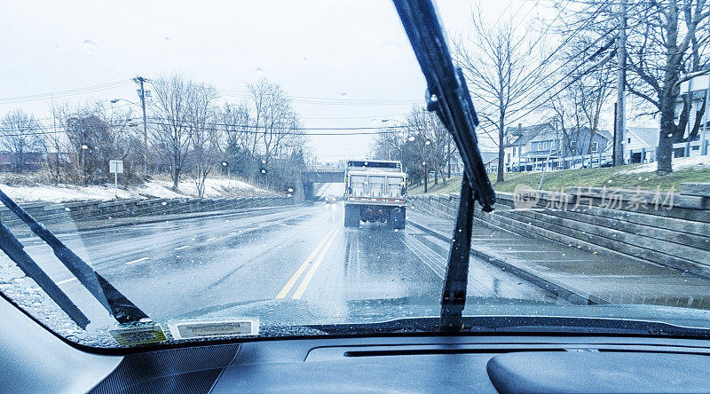在冬季雨夹雪风暴中，汽车司机POV在道路盐车后面