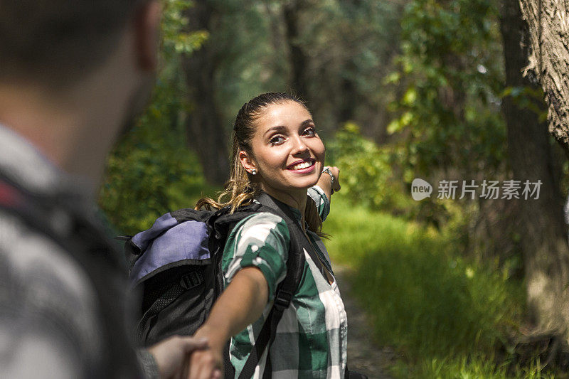 年轻夫妇手牵着手在森林中徒步旅行