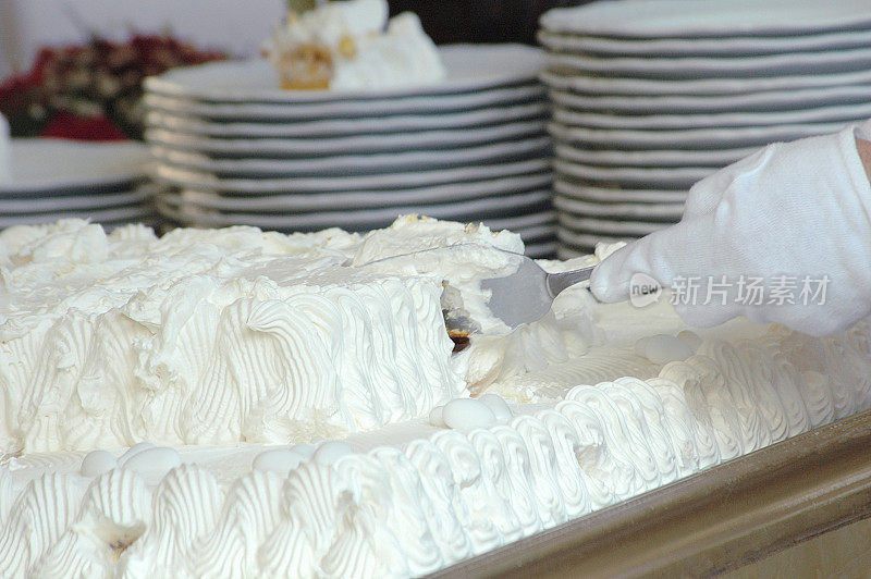 服务员正在切白色婚礼奶油蛋糕