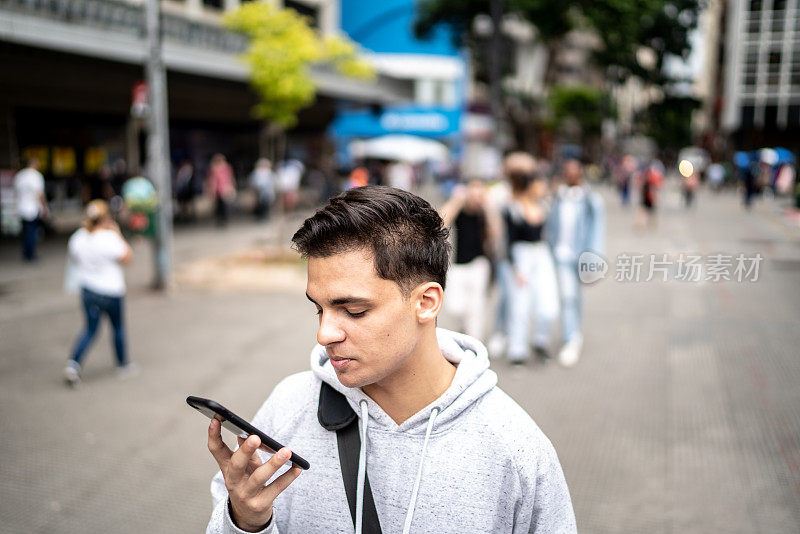 一个年轻人在街上用智能手机