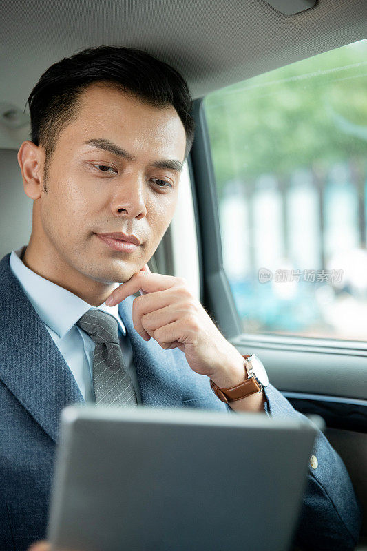 商务男士坐在汽车里看平板电脑