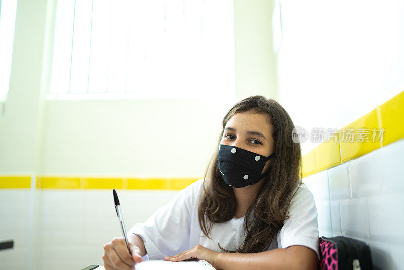 一个女学生在教室里用面具学习的肖像