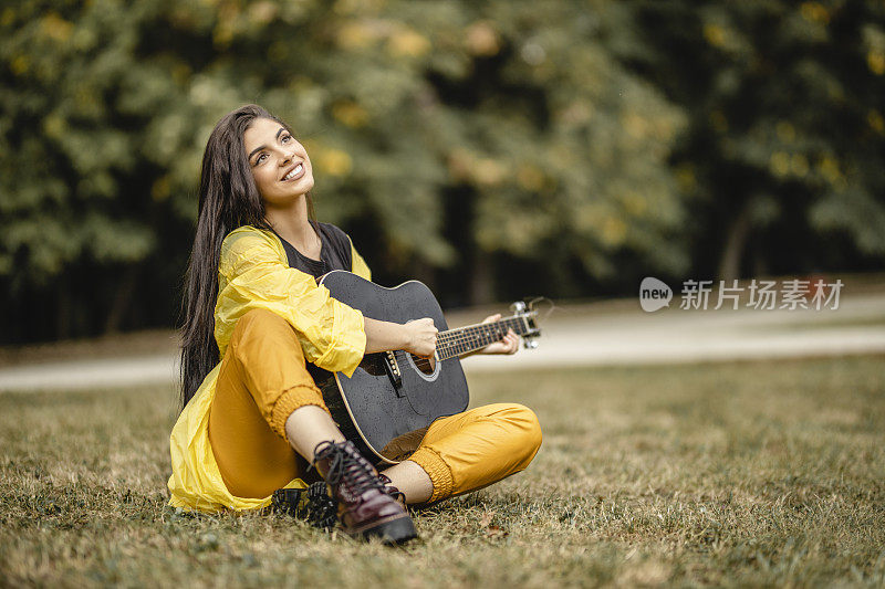 美丽的年轻女子在户外弹奏原声吉他