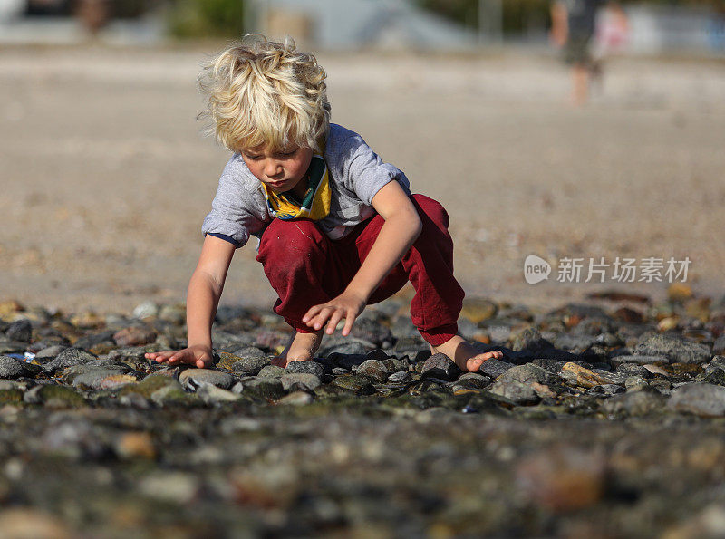 一个在海滩上寻宝的小男孩。