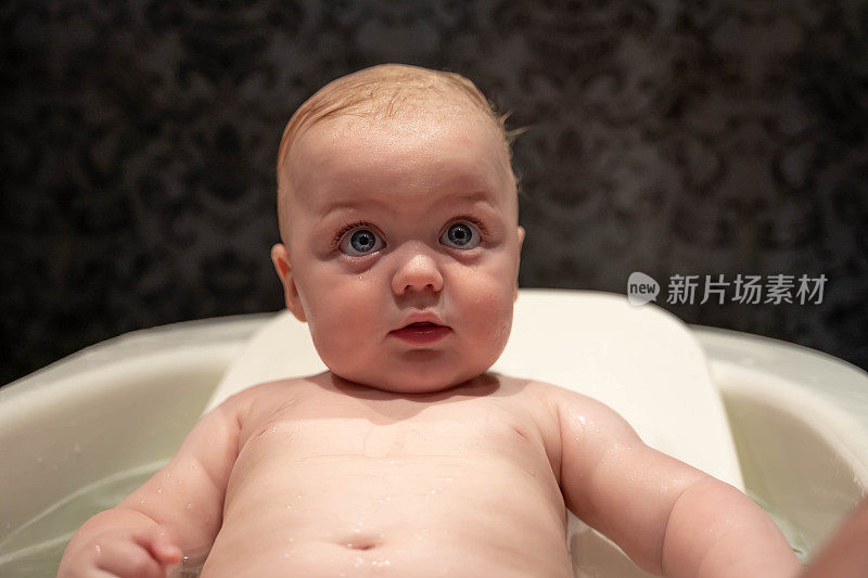 一个可爱的小男孩洗澡的肖像在浴缸里玩，真实的人，7个月大，高加索婴儿男孩